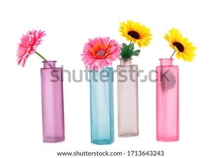 Colorful fabric daisies in glass vases isolated on white background.