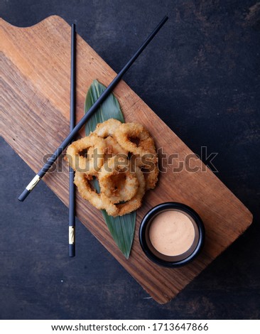 Squid rings tempura with sauce, Japanese sticks and bamboo leave on background