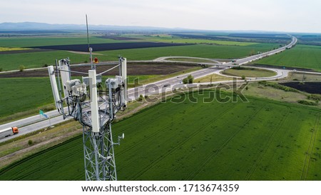 Aerial shot of telecommunication tower with highway on the back. Telecom tower antennas and satellite transmits the signals of cellular 5g 4g 3g lte mobile signals to the consumers and smartphones. Royalty-Free Stock Photo #1713674359