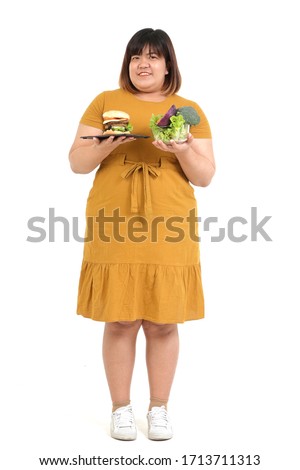 Asian fat woman holds hamburger and salad bowl. On a white background. Weight loss concept Choosing food that is good for the body and health. isolated