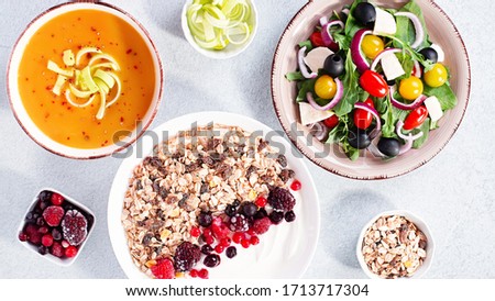 Carrot cream soup, Greek salad, granola bowl with yogurt on concrete table top with copy space. Assortment of dishes for diet, suitable for volumetrics diet and other nutrition strategies, top view Royalty-Free Stock Photo #1713717304