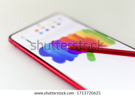 drawing with a stylus on a tablet, smartphone on a white background. creation
The image is painted on the screen of a smartphone. colors of rainbow. digital painting