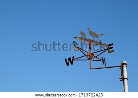 Wind vane isolated on a blue sky background. Wind direction and weather forecasting concept image. 