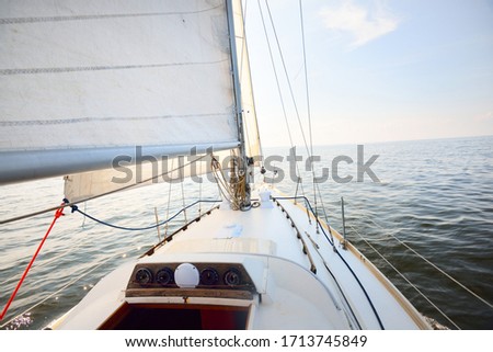 White yacht in an open sea on a clear day. Top down view from the deck to the bow, mast and sails, rigging equipment close-up. Summer Atlantic sailing near Spain and Africa