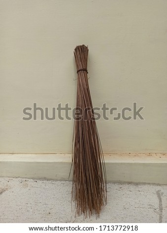 A broom stick made from palm tree leaves.