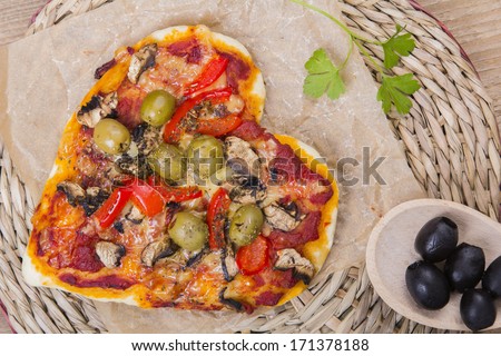 Overhead view of a vegetarian heart shaped pizza served on a wooden table