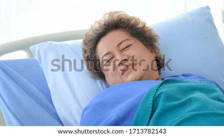 Elderly patient laying on bed in hospital ward                           
