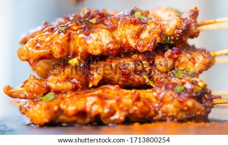 Top view of grilled pork stick image with spicy sichuan pepper sauce.Very hot and spicy taste - Local Thai street food and spicy food style.Picture for appetizer menu.Delicious food in Thailand.