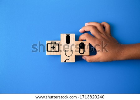 Children hands holding wood cube with a medical symbol,Concept: Health insurance family covid-2019 epidemic,
management protect healthcare to a virus,care service doctor treatment for hospital
