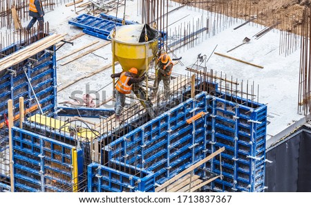 Concreting work at the construction site. Construction workers pour liquid concrete from cement concrete hopper to formwork installation. Royalty-Free Stock Photo #1713837367