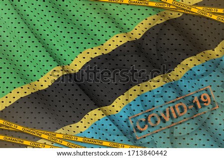 Tanzania flag and Covid-19 biohazard symbol with quarantine orange tape and stamp. Coronavirus or 2019-nCov virus concept