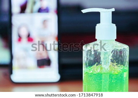 Green gel alcohol With a mixture of aloe vera placed on the work desk, Together with the background of the smart phone and laptop. Video calling on a mobile phone to be social distancing.