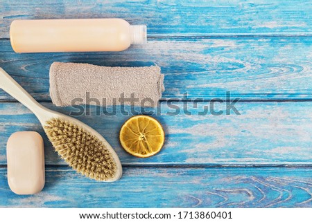 Care products: shower gel, soap,body brush, bath towel and orange circle on a blue tree background. The concept of home Spa.