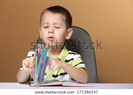 little boy child kid drawing with color pencils on brown background