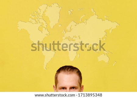 World travel concept with a portrait of a man with a world map on a yellow background. Close up.