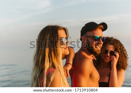 Handsome girls hug a man with a beard on the beach