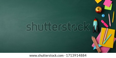 Bright toy rocket and school supplies on chalkboard, flat lay with space for text. Banner design Royalty-Free Stock Photo #1713914884