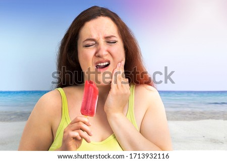 Portrait of a woman with hypersensitivity eating cold ice cream on the beach