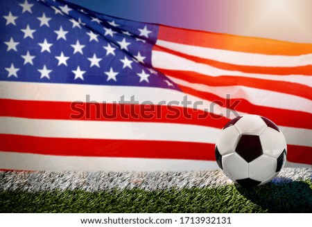 Soccer or football on green grass, on flag of United States of America background