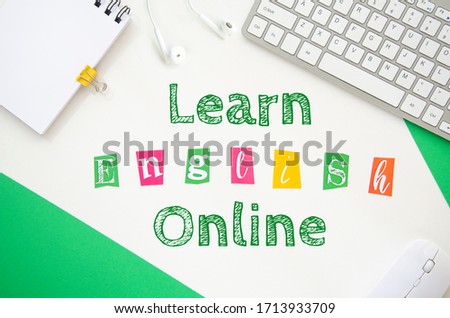 LEARN ENGLISH ONLINE phrase made from cartoon letters framed with school stationery and pc keyboard on a white background. Study at home flat lay
