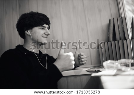 Online banking. Online shopping. A young guy in a yellow hoodie makes an online purchase using his phone and credit card. Close-up photo. Black and white photo.
