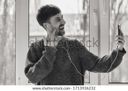 Online communication. The guy communicates in the video chat. Smiling guy is chatting by video chat. A young guy communicates on the phone. Quarantined communication. Black and white photo.