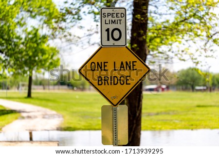 Close up of one lane bridge and speed limit 10 signs posted along road.