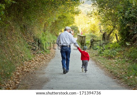Back view of grandfather and grandchild walking in a nature path Royalty-Free Stock Photo #171394736
