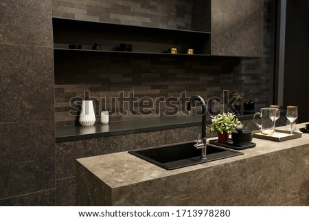 MOSCOW / RUSSIA - 03/04/2019 luxurious spacious modern kitchen island in black grey brown stone marble. a comfortable dining area, a table, a jug, wine glasses, plates on the counter top  Royalty-Free Stock Photo #1713978280