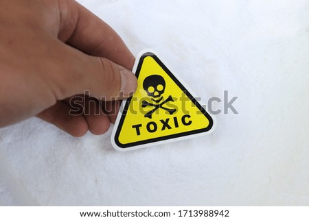 toxicity sign held in hand on white powder background