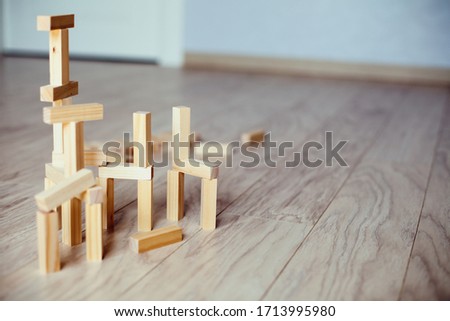 Wooden blocks stand on top of each other, some lie on the floor in a chaotic manner. The concept of business development, the use of non-standard solutions. Games at home as a family