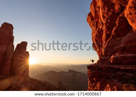 Sunset shining through red cliffs as a yoga silhouette exercises in the distance at Cathedral Rock in Sedona. Royalty-Free Stock Photo #1714000867