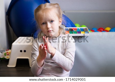 little girl having fun with colorful modeling clay, dough or plasticine