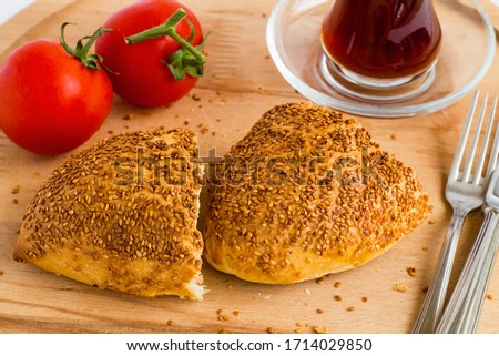 Traditional Turkish Homemade Salty Pastry with sesame sliced on wooden plate with tea and cherry tomato