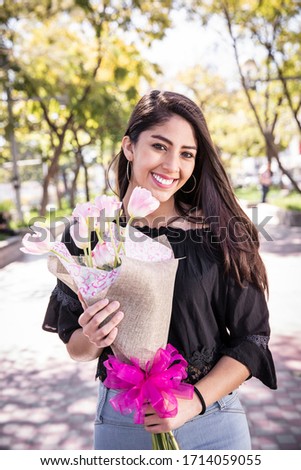 Beautiful young woman in the outdoors with a bouquet of flowers