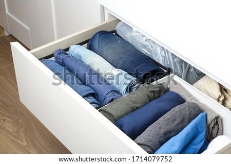 Pants folded according to the method of Marie Kondo. Vertical storage of clothes in a chest of drawers. Storage organization. Order and cleanliness. Quarantine, self-isolation, housework. Royalty-Free Stock Photo #1714079752
