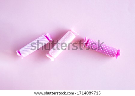 Three candy in polka dot wrapper on pink background. Lip balm pack. 