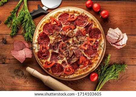 whole salami pizza with sausage top view with attributes on wooden background