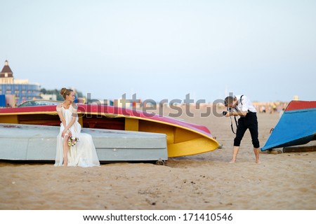 Bride posing while her groom is shooting with an old camera