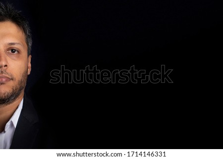 Half face portrait of handsome man smiling with little beard and with black background