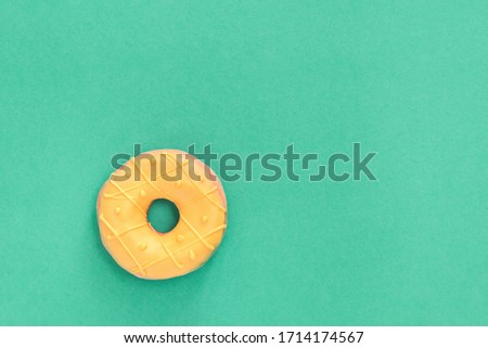 One tasty fresh Donut with yellow glaze on trending green background. Top view minimal flat lay with copy space