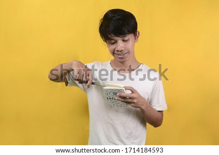 portrait of Asian man cutting paper isolated on a yellow background
