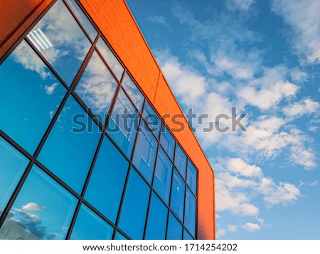 high modern brick business building with large glass windows reflecting blue sky with clouds. modern design concept