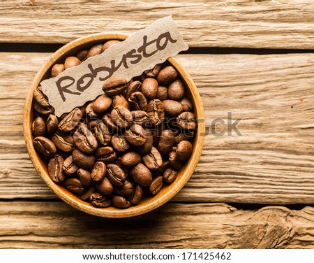 Bowl of Robusta coffee beans over an old wooden table Royalty-Free Stock Photo #171425462