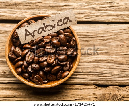 Bowl full of Arabica coffee beans over an old wooden table Royalty-Free Stock Photo #171425471