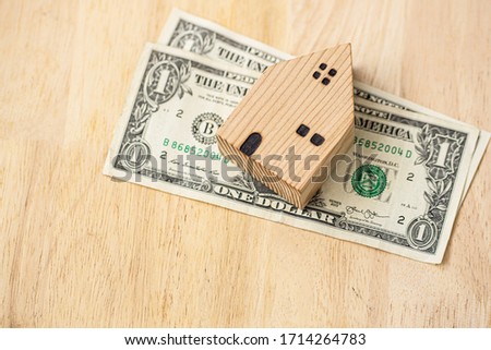 Home put on a dollar Which is resting on a wooden table Used as a picture showing the loan to buy a house Purchase real estate Saving money for real estate purchase. saving and investment concept.