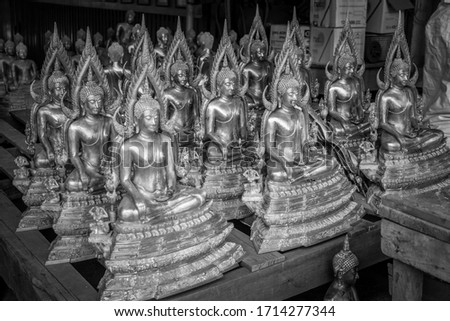 Several Buddha statues are displayed on a table in black and white.