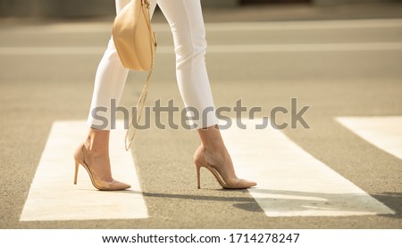 Close up of woman legs walking on crosswalk. The woman is wearing shoes on high heels. Royalty-Free Stock Photo #1714278247