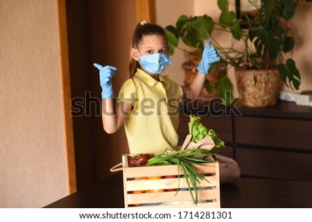 Coronavirus. Young woman with face mask on quarantine, cooks in the kitchen at home during coronavirus crisis. Stay at home. Enjoy cooking at home. Family concept.