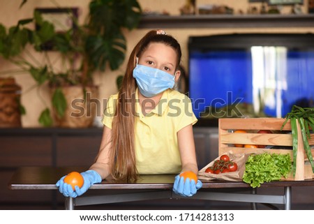 Coronavirus. Young woman with face mask on quarantine, cooks in the kitchen at home during coronavirus crisis. Stay at home. Enjoy cooking at home. Family concept.